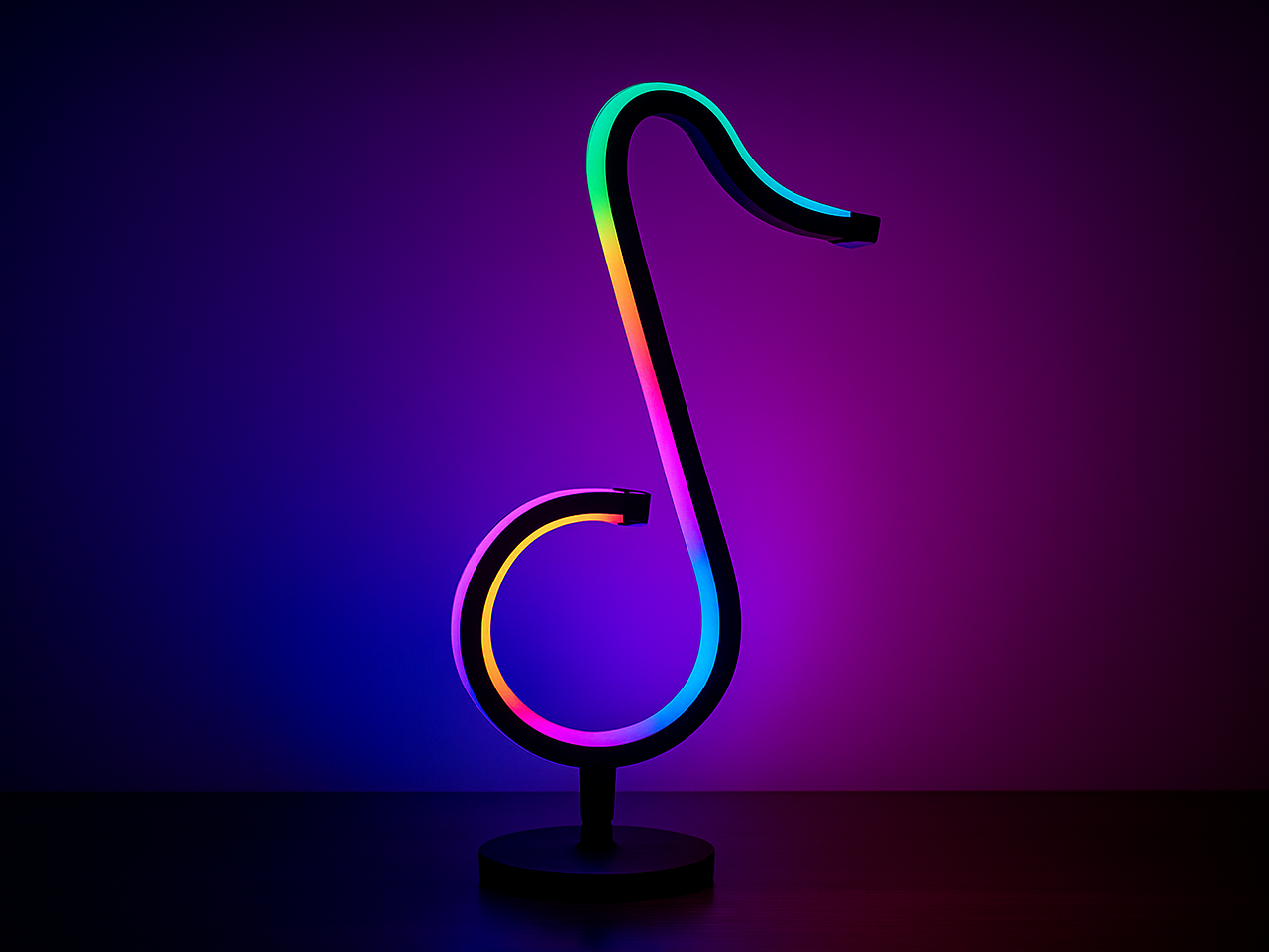 Stylish RGB table lamp shaped like a treble clef, glowing in multicolor hues against a purple and blue gradient wall.
