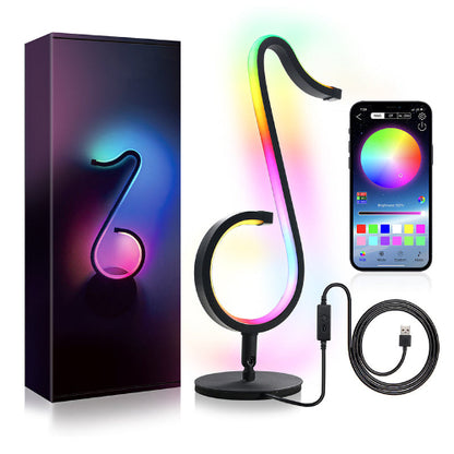 Colorful LED lamp shaped like a treble clef with smartphone app control, packaging, and USB cable.
