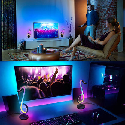 Living room with a TV displaying a concert scene, and a home office setup with a computer monitor and desk.